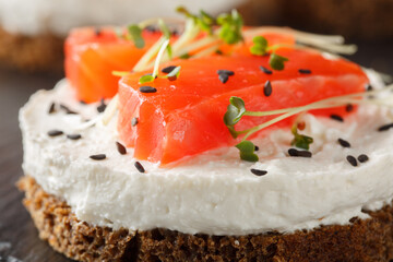 Spicy savory cheesecake with red fish, cream cheese, sesame and microgreens close-up on slate plate on table. Horizontal