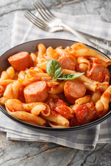 Italian Treccione pasta served with tomato, onion, sausage and basil close-up in a bowl on the table. Vertical