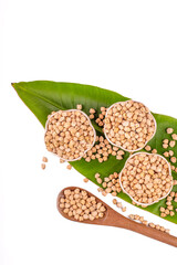 Dried chickpeas in white bowl on white. Spilled chickpeas.