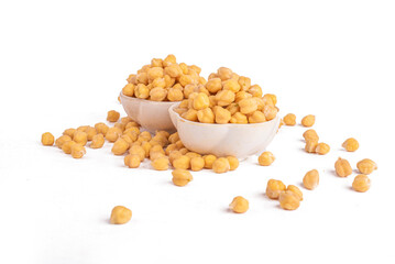Dried chickpeas in white bowl on white. Spilled chickpeas.