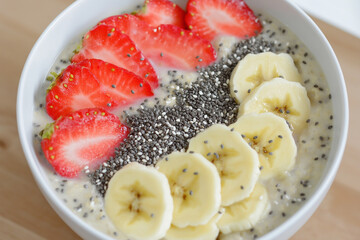 Editorial photo of oatmeal bowl with bananas, strawberries, and chia seeds