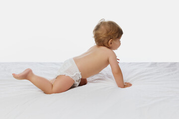 Obraz premium Early development. Baby crawling away, showing back and diapered bottom against white studio background. Concept of parenthood, childhood, lifestyle, natural beauty, love and care. Ad.