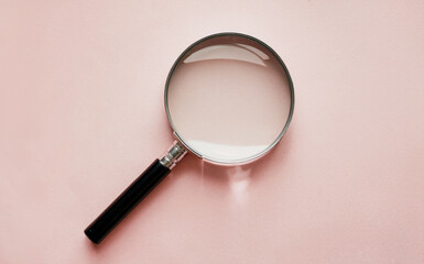 The image featuring a magnifying glass placed prominently against a soft pink background