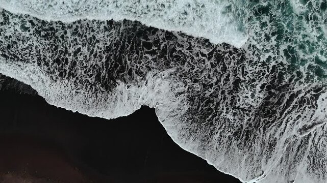Bali black sand beach with huge waves at Pantai Purnama. Aerial cinematic 4k video. Beautiful Bali nature coastline from above.