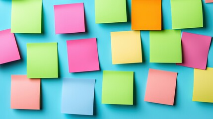 Colorful sticky notes scattered on a blue surface, showcasing different shapes and vibrant hues for organizing thoughts or reminders.