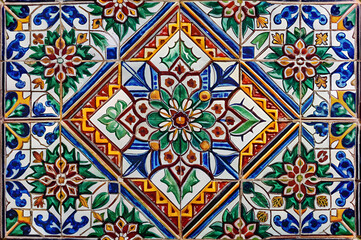 A vibrant, decorative tile design featuring intricate floral patterns in blue, green, yellow, and red colors, arranged in a symmetrical layout.