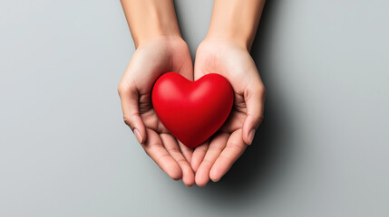 Two hands gently holding a bright red heart-shaped object on a neutral gray background, symbolizing love and care.