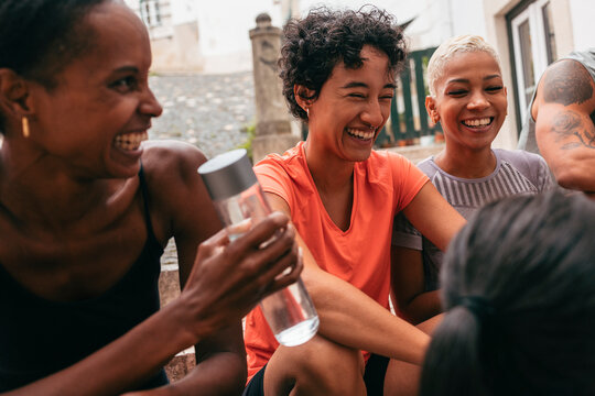 Group of diverse female athletes laughing together after city workout - Powered by Adobe