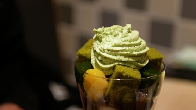 close up view to beautiful parfait sweet dessert in japanese style full with ice cream mochi green tea yelly and topped with green tea cream in japanese minimal cafe