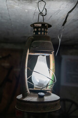 Kerosene lamp. Old metal lantern glass bulb in basement dark.