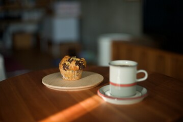 木の皿に乗せたマフィンとホットコーヒー
