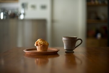 木の皿に乗せたマフィンとホットコーヒー