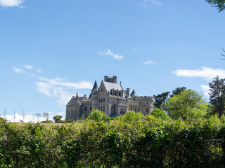 Panoramic view of the impressive Château d'Abbadie in the south of France, built on a hill, on a sunny day with a clear blue sky.