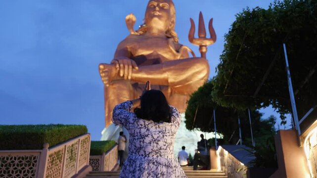 young girl prying for lord shiva at outdoor at evening video is taken at statue of belief nathdwara rajasthan india.