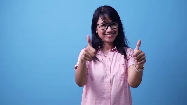 Happy young Asian woman presenting something at copy space for product or sign text. Isolated on blue background in studio.