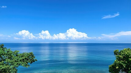 Tranquil ocean view, bright blue sky with soft white clouds above the horizon