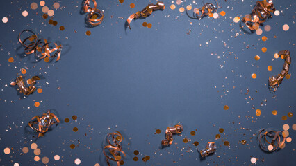 Silvester, New Year's eve, birthday party, christmas or other celebration greeting card - Frame border made of orange confetti and gift ribbons , isolated on blue table background, flat lay, top view