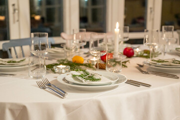 Festively decorated dinner table set for a Christmas celebration, with lit candles, fresh greenery, and seasonal decorations, exuding a warm and inviting holiday ambiance