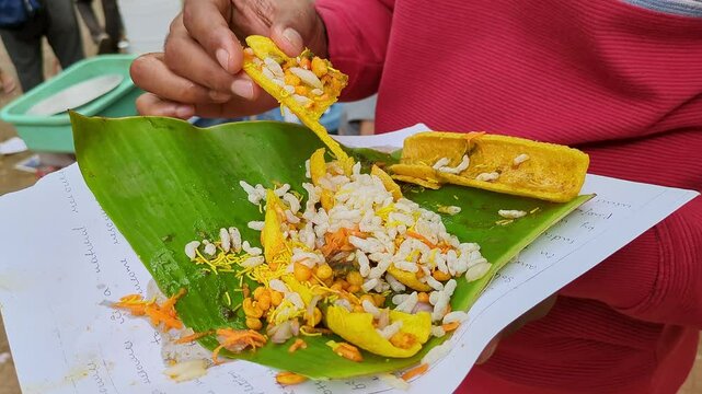 Man eating boti masala chaat or crunchy fryums with salad, chutneys, puffed rice, sev