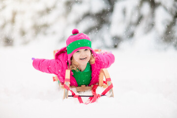 Child playing with snow in winter. Kids outdoors.