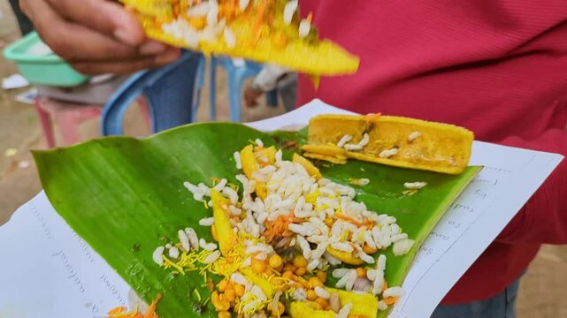 Man eating boti masala chaat or crunchy fryums with salad, chutneys, puffed rice, sev
