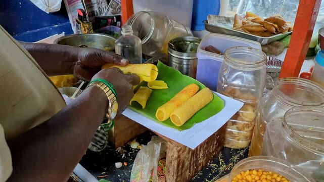 A man preparing boti masala chaat or crunchy finger fryums with salad and chutneys
