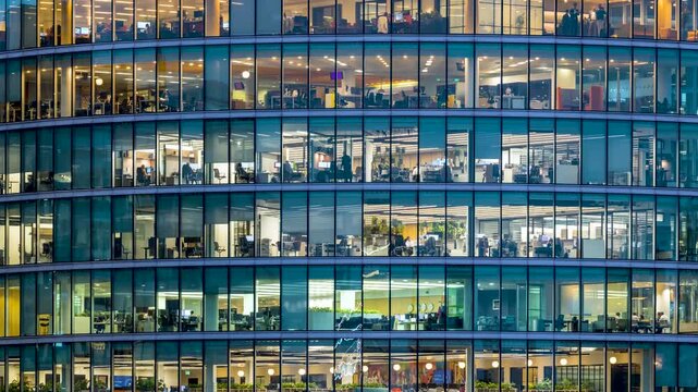 Timelapse view of an modern office building during evening with lights and workers movement