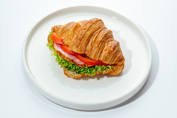croissants stuffed with ham and vegetables on a white background