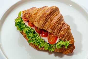 croissants stuffed with ham and vegetables on a white background