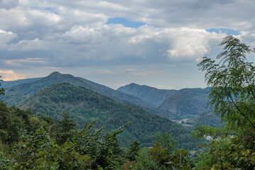 vista su un ambiente collinare e naturale nella Slovenia occidentale, di pomeriggio, con il cielo nuvoloso, in estate