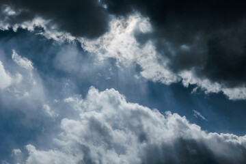 dettagli di grosse nuvole scure che oscurano il cielo azzurro, di giorno, illuminate dal sole