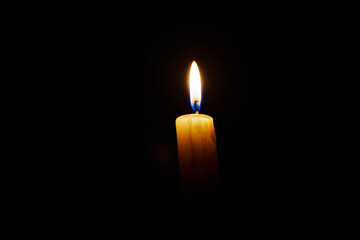 Close-up single candle burning on dark black background, candle fire flame light.