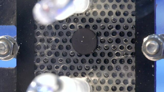 Hydrogen gas bubbles forming on the membrane of an electrolyzer, splitting water into hydrogen and oxygen using electric energy. Macro shot, Full HD crop.