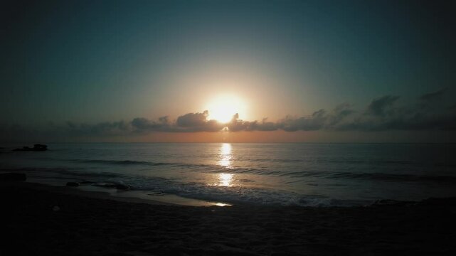 Beach sunrise time lapse with sun rising behind the clouds