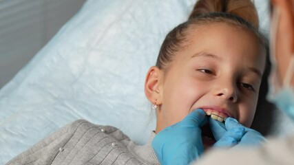 Orthodontist explaining dental braces for teeth correction. Dentist showing how to use teeth retainers for child