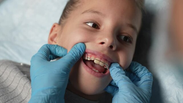 Orthodontist explaining dental braces for teeth correction. Dentist showing how to use teeth retainers for child