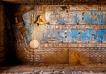 Ancient Egyptian relief features detailed carvings of figures and hieroglyphics on a stone surface.The scene depicts individuals engaged in activities, possibly of religious or ceremonial significance