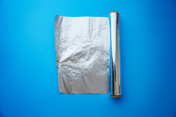 A roll of baking foil on a blue background. devices for delicious dishes in the kitchen.
