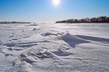 Winter snow desert with the picturesque snowdrifts on the foreground and icicles at the field at the sunset - shallow depth of filed, winter desert landscape