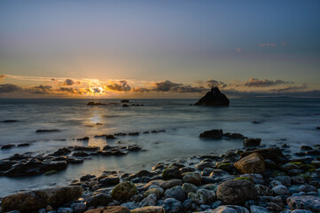 Sunset behind some clouds on a rocky beach, Portugal