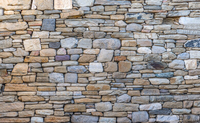 Textured seamless background of an ancient stonewall with different shaped and sized stones