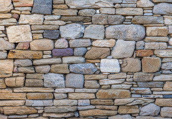 Textured seamless background of an ancient stonewall with different shaped and sized stones