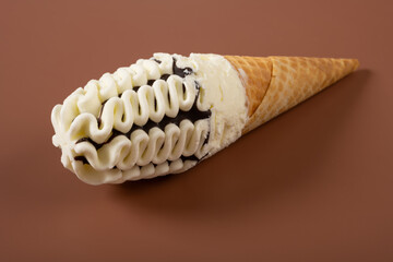 angle view vanilla and chocolate flavor ice cream cone on a brown background