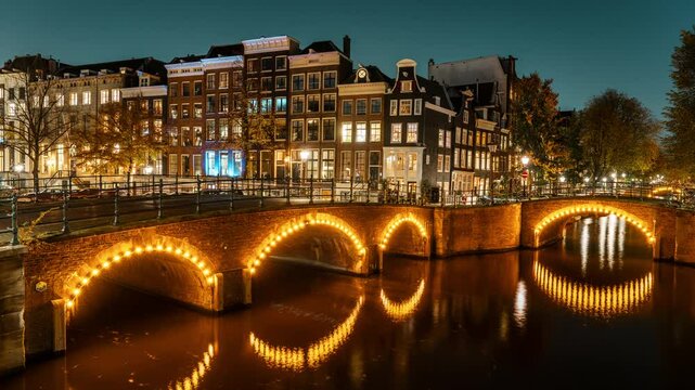 Timelapse of Amsterdam&rsquo;s historic canal bridges illuminated at night. The Keizersgracht and Reguliersgracht intersection glows beautifully, reflecting typical Dutch architecture in the water