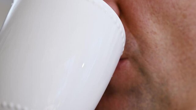 close-up. A man drinks hot coffee from a white cup. Morning invigorating drink.