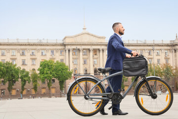 Fototapeta premium Young happy businessman with bicycle on city street