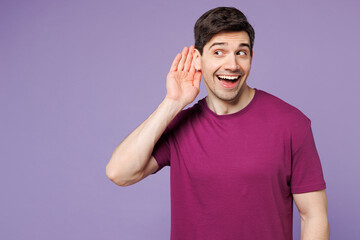 Young curious nosy Caucasian man he wear violet t-shirt casual clothes try to hear you overhear listening intently isolated on plain pastel light purple background studio portrait. Lifestyle concept.