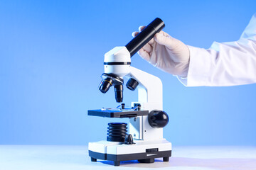 Scientist's hand with modern microscope on white table