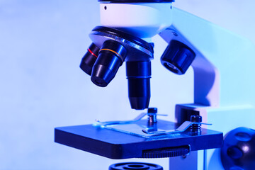 Modern microscope on blue background, closeup