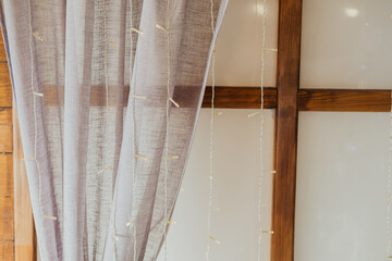 Soft gray curtain drapes beside wooden framed wall in a cozy indoor space